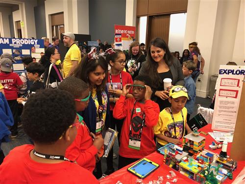 Students looking at legos on a table 